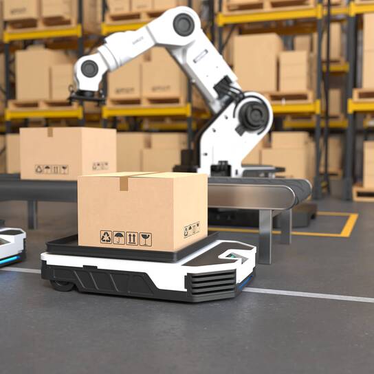 R3 - BUSINESS AREAS - Robot arm A robotic arm autonomously lifts a cardboard box in a warehouse setting with shelves full of packages.