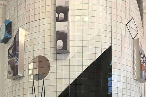 A geometric art installation combines tiles and 3D elements on a curved wall, featuring abstract shapes and architectural photos.