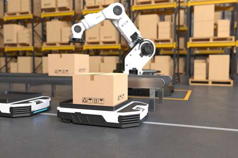 Ein Roboterarm hebt eine Kiste auf ein autonomes Transportfahrzeug in einem Lager voller Kartons.