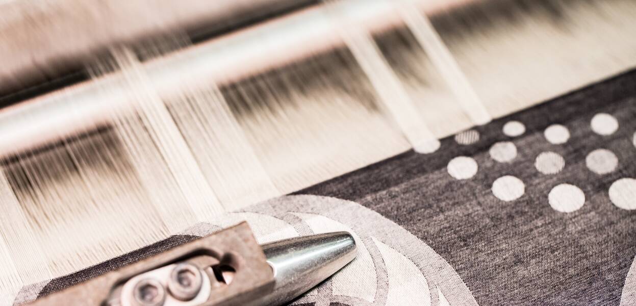 A textile loom weaves intricate patterns with precise threads, showcasing the art of fabric creation.