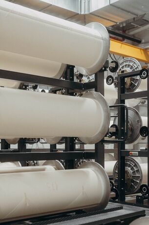 Mehrere große Rollen weißen Materials sind in einem industriellen Lagerregal bei Ertex International angeordnet.