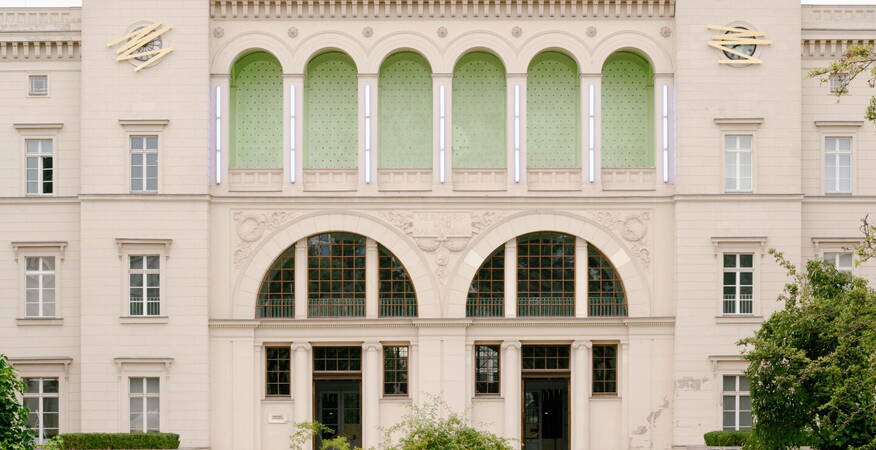 The grand facade of LaForgia features green accents and elegant architecture, framed by lush garden pathways. (Text KI-generiert)