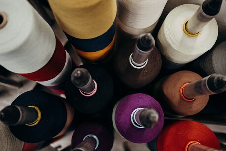 Bunte Garnrollen in verschiedenen Farben stehen dicht beieinander, perfekt für kreative Nähprojekte.