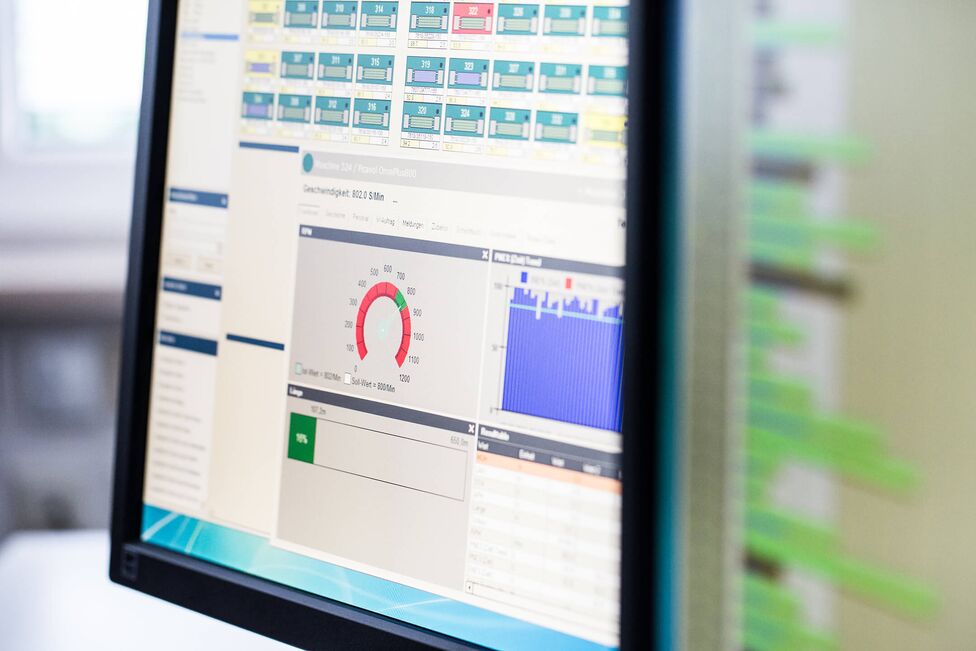 A computer monitor displays detailed analytics and performance data, featuring colorful graphs and speed gauges.