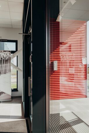 Ein heller Eingangsbereich mit einem großen Schwarz-Weiß-Foto und einer roten Tür, inspiriert von Ertex International.