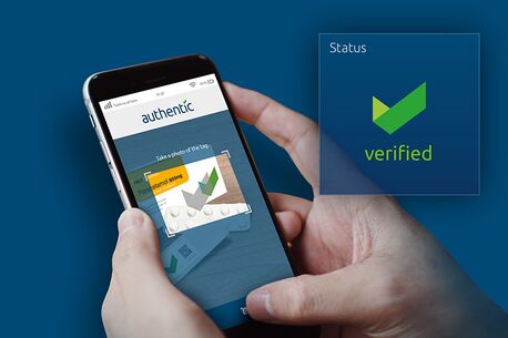 Ein Smartphone zeigt eine App mit dem Wort "authentic" und einem "verified"-Status für ein Medikamentenbild.