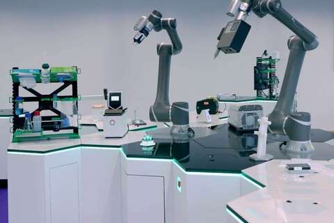 In einem modernen Labor arbeiten kollaborative Roboterarme an einer Hightech-Insel mit integrierten Geräten.
