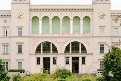 Die majestätische Fassade des HBF zeigt grüne Fenster und einen einladenden Gartenweg. (Text KI-generiert)